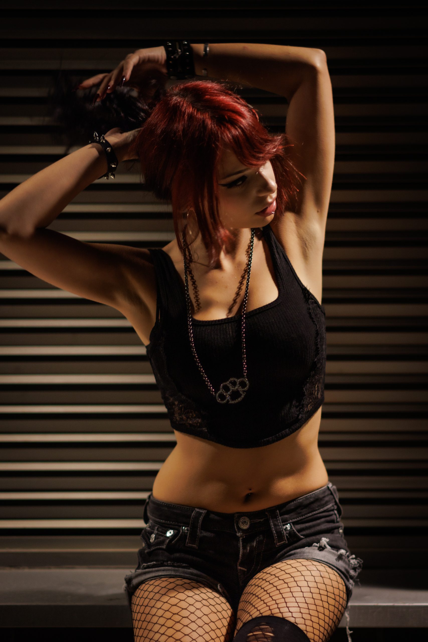 Woman with red hair in a black crop top and denim shorts, industrial setting