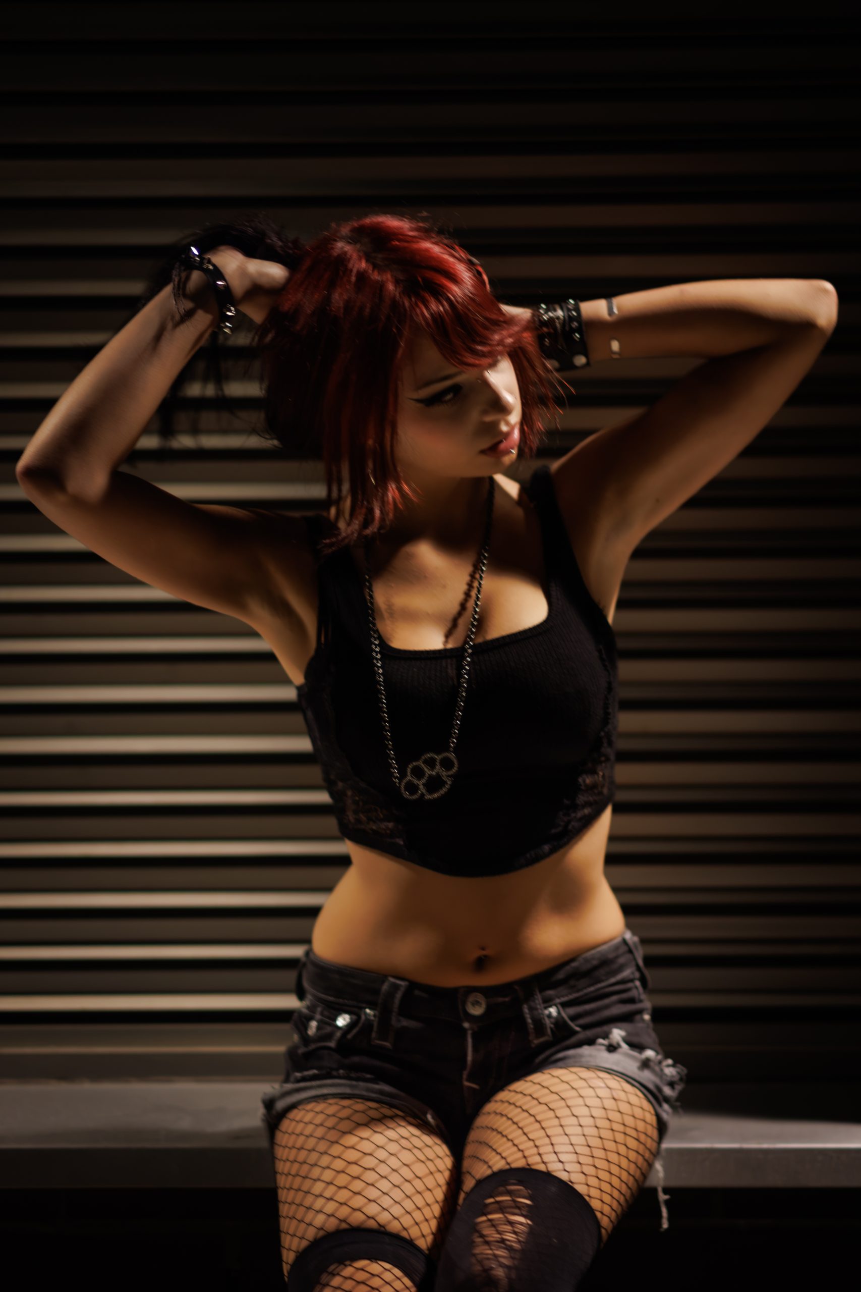 Woman with red hair, hands in her hair, dramatic side lighting