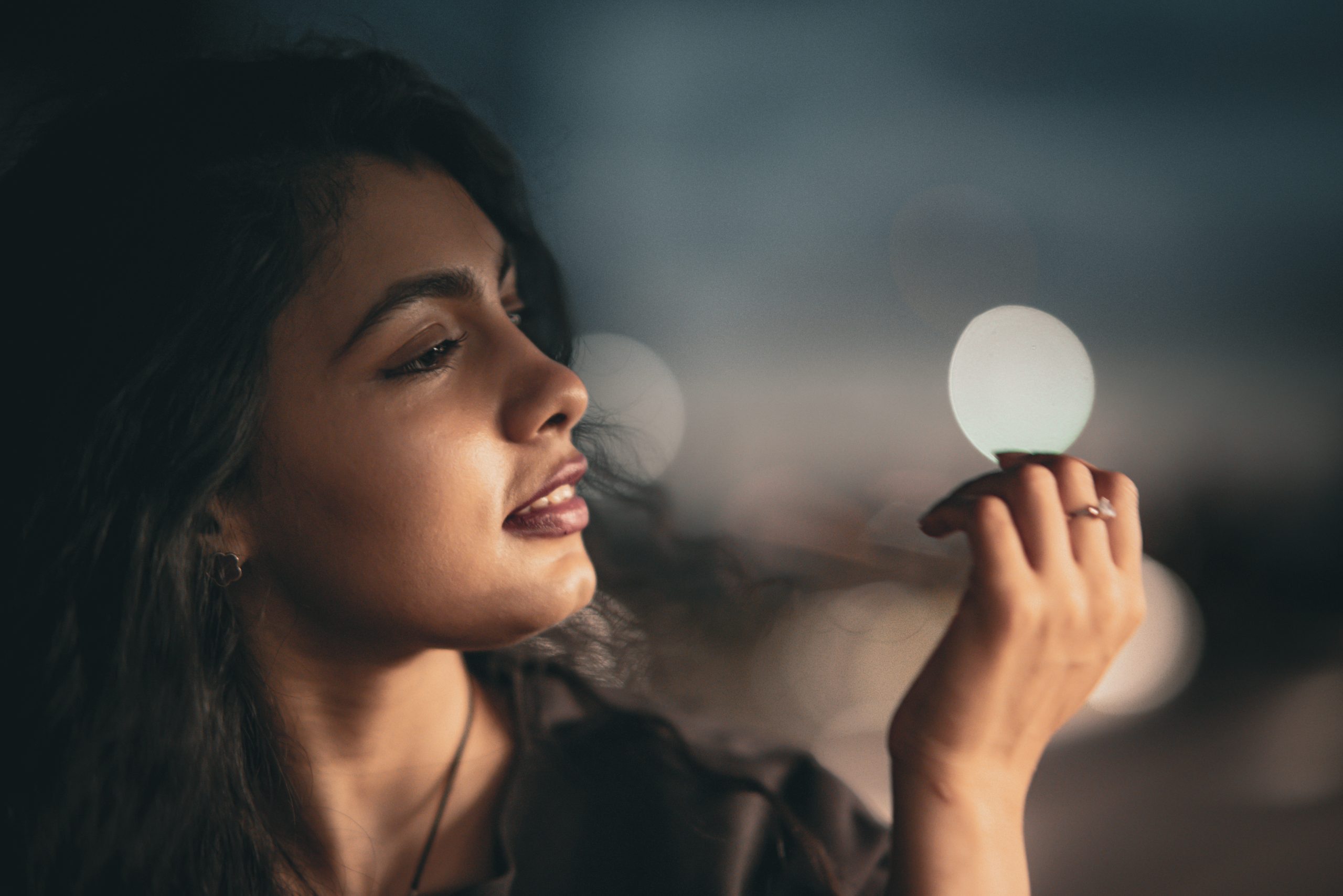 Woman in profile holding a glowing sphere, soft ambient light