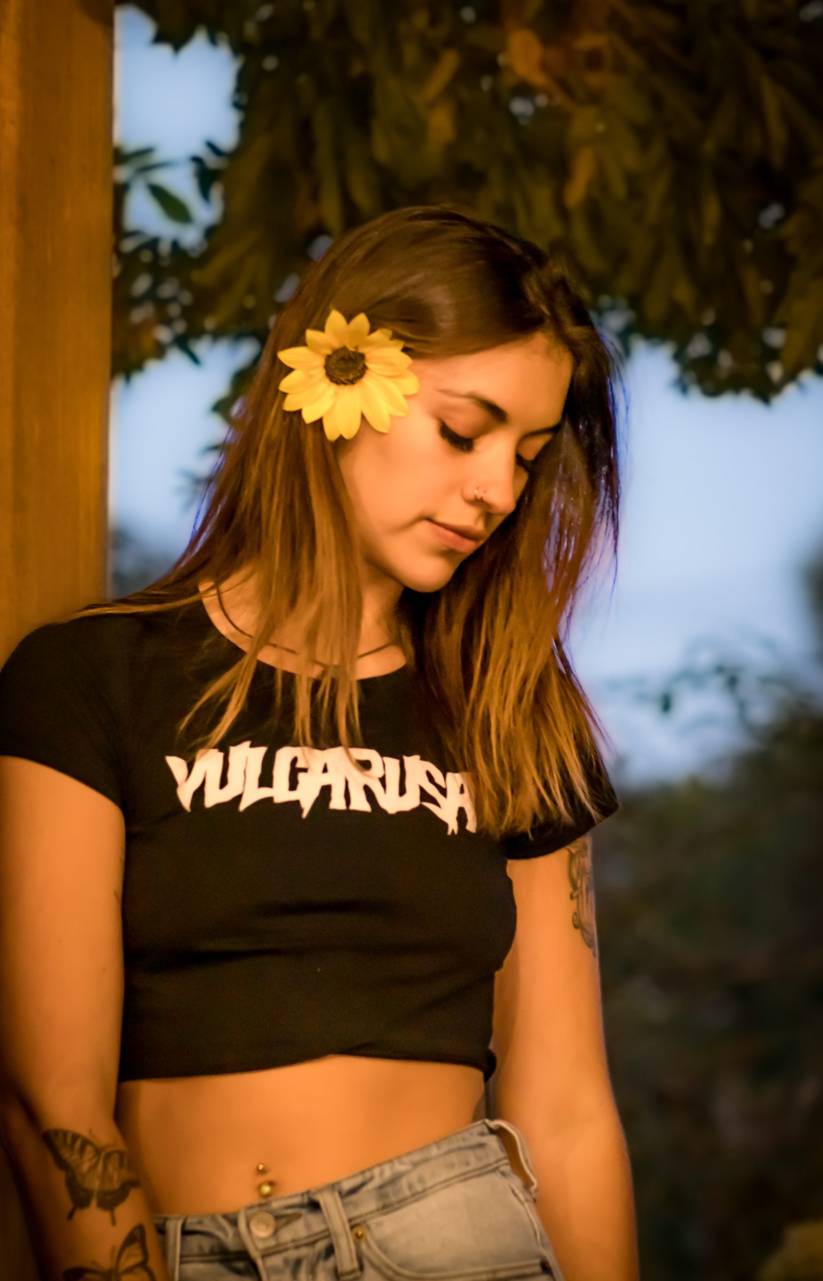 Woman with a sunflower in her hair, black graphic t-shirt, soft daylight