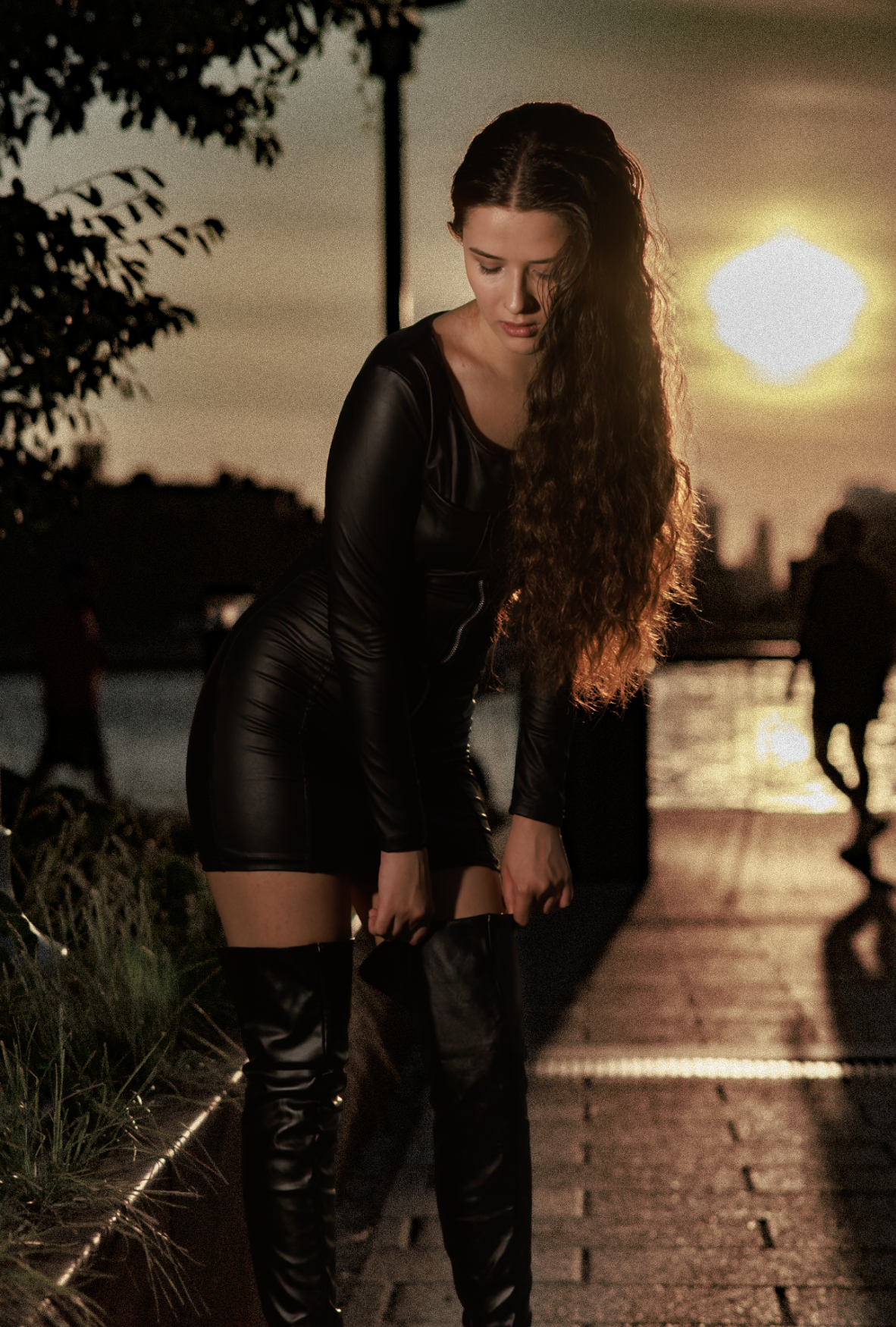 Woman with curly hair in a black leather outfit, golden hour by the water