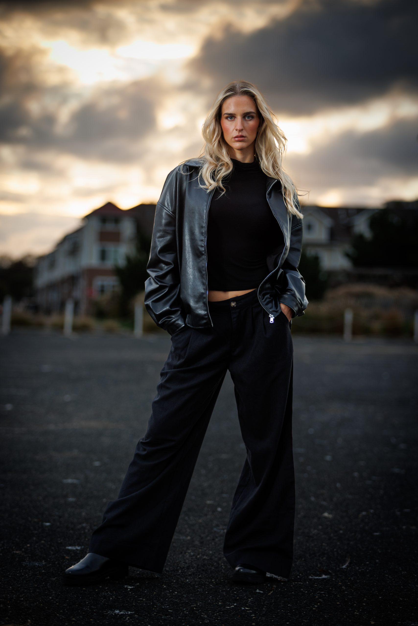 Woman in a leather jacket and wide-leg trousers, alternate framing, dusk light